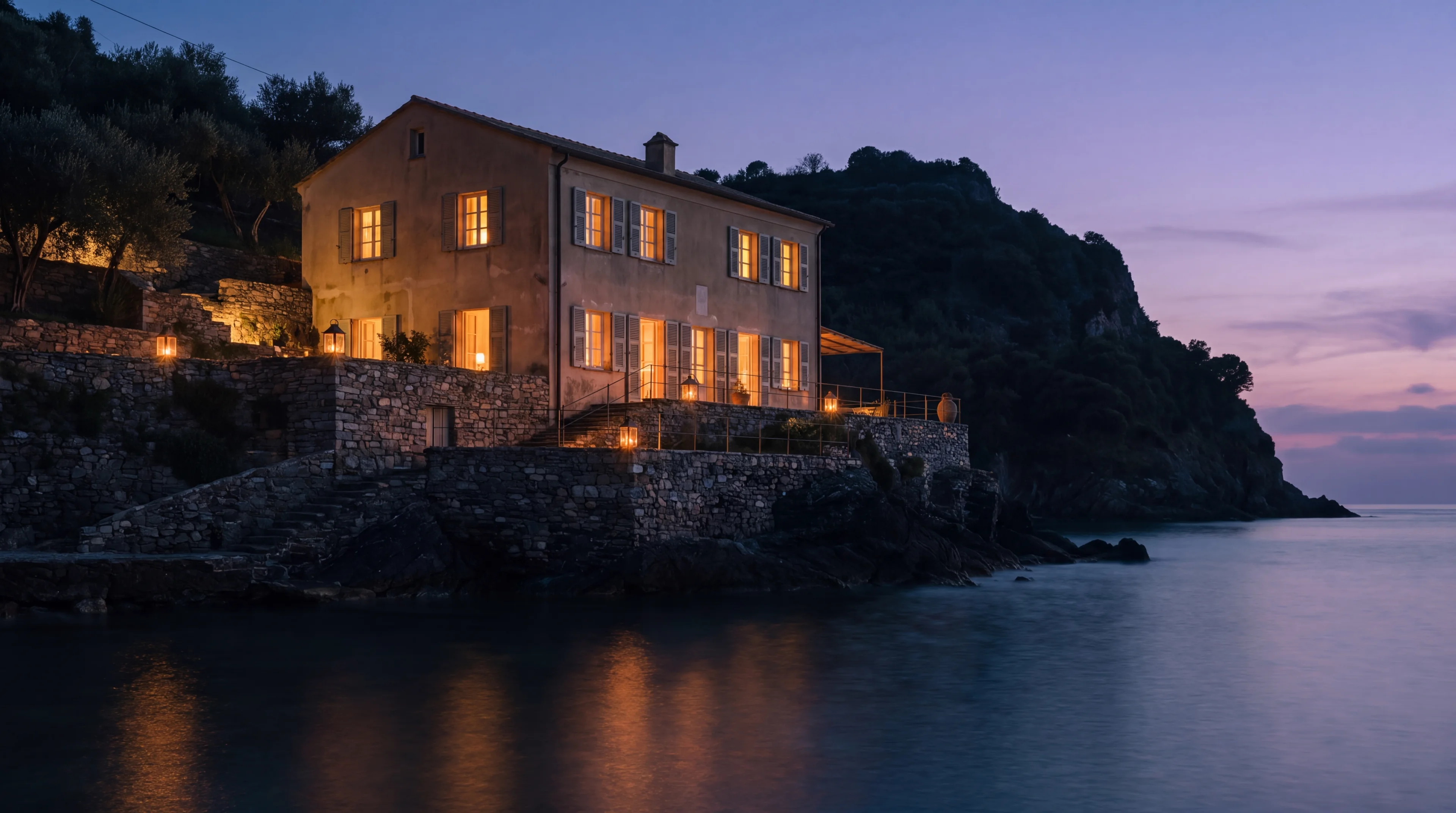 The house at night seen from the water, every window lit