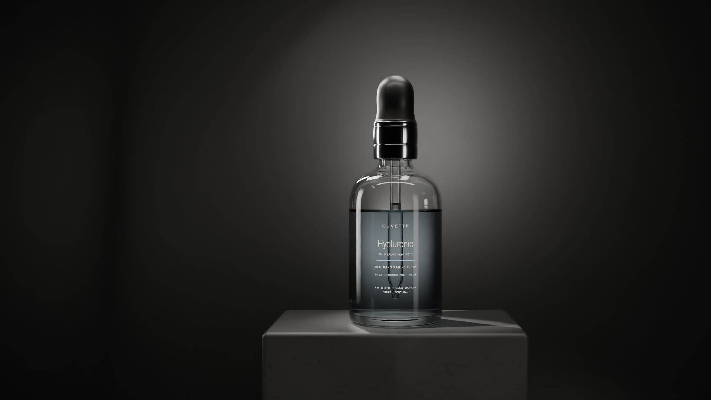 Hyaluronic 2% serum in a glass dropper bottle on a basalt plinth under a single light
