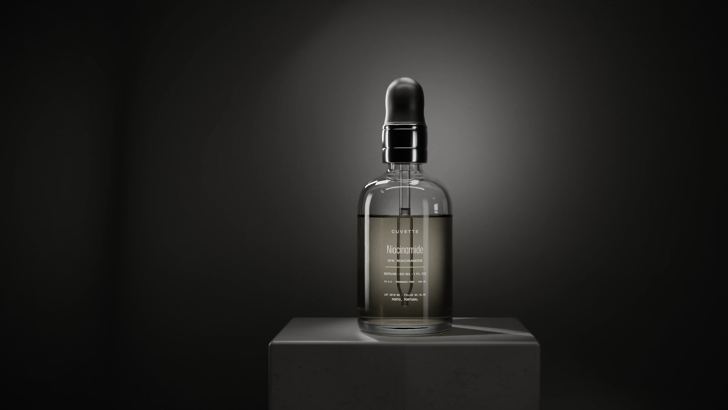 Niacinamide 10% serum in a glass dropper bottle on a basalt plinth under a single light